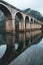 A bridge spans a river with a reflection of the bridge in the water