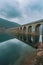 A bridge spans a river with a reflection of the bridge in the water