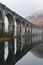 A bridge spans a river with a reflection of the bridge in the water