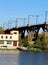 The bridge that stands in the water. The bridge over which freight trains move. Nearby is the river and the building.