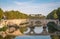 Bridge on Tiber river in Rome, Italy. Vatican Basilica cupola in background with sunrise light