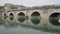 Bridge of Tiberius arches reflected in calm river