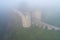 Bridge and towers of the Koporye fortress in dense morning fog