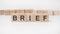 brief word, text, written on wooden cubes, building blocks, over white background