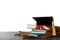 Briefcase with books, diploma and graduation hat on table