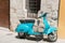 Bright aqua motor scooter parked in Italian village street.