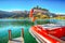 Bright autumn view of San Valentino village and Muta lake Haidersee and resque boat