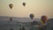 Bright balloons float above rocky valley against clear sky