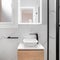 Bright bathroom boasts a sleek and minimalist style, featuring a gleaming white sink set against a stunning black framed