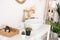 bright bathroom, sink, mixer, mirror, wicker basket and flowers on a white cabinet.