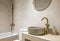 Bright bathroom in soothing pastel colors with textured ceramic tiles. Attractive oval sink. Faucets made of copper in