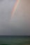 Bright beautiful colorful full arc rainbow over the sea
