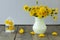 bright, beautiful, yellow dandelions in vase and cages with flowers on wooden table. spring or summer flowers on grey