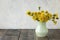 bright, beautiful, yellow dandelions in vase on wooden table. spring or summer yellow flowers on grey background