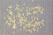 Bright beautiful yellow sparkles scattered on a gray textured background, close up
