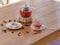 A bright berry tea in a glass teapot next to a transparent glass, a round white plate and dried fruits on a wooden