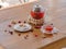 A bright berry tea in a glass teapot next to a transparent glass, a round white plate and dried fruits on a wooden