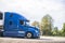 Bright blue big rig long hauler semi truck with refrigerated semi trailer and grille guard driving on the road for delivery
