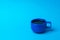 A bright blue cup with black coffee on a blue background