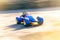 Bright blue gokart zooming around the track with its white wheel clearly visible. Speed drive concept. AI generation