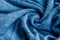 Bright blue knitted fabric texture. Crumpled twisted blanket background