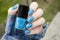 Bright blue Nail art manicure. Holiday style nails with neon glitter. Woman holds Bottle of Nail Polish