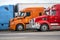 Bright blue orange and red big rig semi trucks standing on row on the truck stop waiting for continue delivery