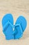 Bright blue rubber flip flops on the sand