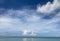 the bright blue sky with the amazing cloudscape reflects on the ocean