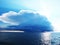 Bright blue sky with stormy clouds over a sea