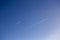 Bright blue sky with two vapour trails