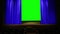 a bright blue theatrical curtain in the auditorium moves to the sides behind it a green background