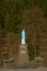 Bright blue and white statue of Lady Mary praying on a brick pedestal