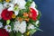 Bright bouquet of gerbera chrysanthemum lily green leaves on a dark background close-up.