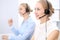 Bright call center office. Two blonde women in a headset