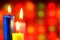 Bright candles burn on the background of festive Christmas lights. A candle symbol of faith, hope and life