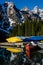 Bright canoes at moraine lake with snow covered rockies in background