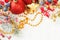 Bright Christmas composition with red baubles, holly berries, Xmas tree branch and golden garland on white snow background