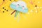 Bright cloud pinata and confetti on yellow background, flat lay. Space for text