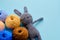 Bright color yarn clews with grey stuffed amigurumi bunny on the blue background. Concept of amigurumi toy making, handcrafting,