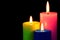 Bright colored candles burning on a black creative background. Candles illuminate, and symbol of faith, hope, love, holiday of