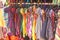 Bright colored children`s dresses or sarafans hang on hangers and are sold in the market of bazaars in India. Showcase with