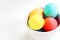 Bright colored Easter eggs nested in a white bowl.