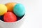 Bright colored Easter eggs nested in a white bowl.