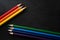 Bright colored pencils on a dark black background. Seven colors of the rainbow. Back to school. Education and creativity. Drawing