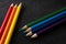 Bright colored pencils on a dark black background. Seven colors of the rainbow. Back to school. Education and creativity. Drawing