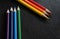 Bright colored pencils on a dark black background. Seven colors of the rainbow. Back to school. Education and creativity. Drawing