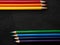 Bright colored pencils on a dark black background. Seven colors of the rainbow. Back to school. Education and creativity. Drawing