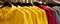 Bright colorful autumn raincoats hanging at a fashion store. Closeup of multi-colored yellow, red, grey, waterproof raincoats hang