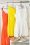 bright colorful dresses hanging on coat hanger, shoes and handbag in white wardrobe